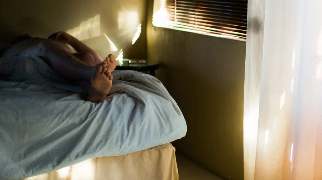 photo of person lying down in bed showing mostly their feet