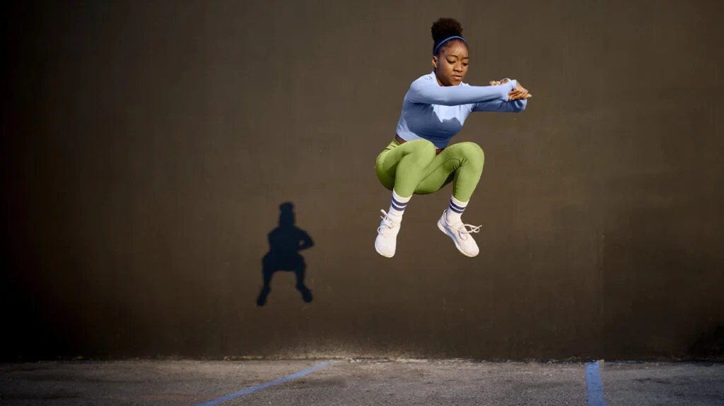 A young woman leaps high into the air during a jumping exercise